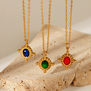 Three gold titanium necklaces with blue, green and red gemstone cross pendants