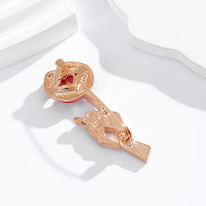 Creative gold-plated lip brooch with safety pin fastener on a white textured background