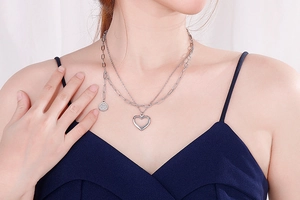 Detail of silver double-layered necklace with heart pendant and paperclip chain