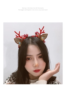 Close-up of Christmas reindeer antler headband with berries and pine cones on a model
