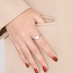 Detail shot of a minimalist heart ring with white shell inlay worn by a model