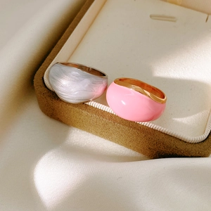 Close-up of minimalist enamel rings in pearl grey and pink with polished metallic bands