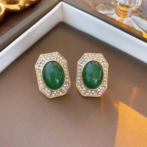 Close-up of vintage gold earrings with green gems and rhinestones in a brown box