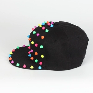 Detail der schwarzen Flatbrim-Kappe mit auffälligen bunten Punk-Spikes und Nieten-Verzierung
