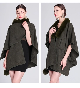 Detail view of olive green knit cape featuring a plush faux fur collar and pom-pom charm