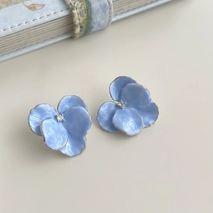 Macro shot of light blue three-petal flower stud earrings with a central white rhinestone