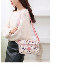 Detailed view of polka dot crossbody bag with adjustable pink strap on a model