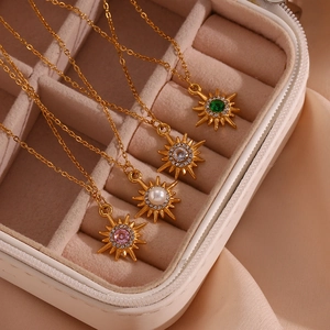 Detail of 18K gold starburst necklaces with pearl and zircon inlay in a velvet box