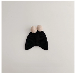 Detail of black ribbed knit baby hat with a contrast cream-colored bow decoration