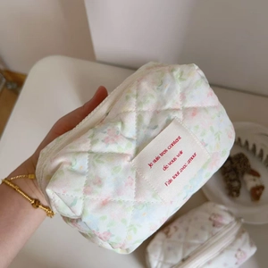 Detailed macro view of floral quilted cotton makeup bag with French script label