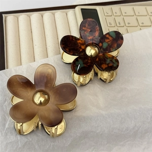 Detail view of acetate flower hair claws with amber marble and tortoiseshell patterns
