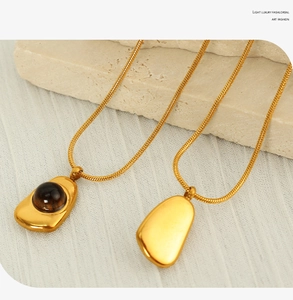 Detailed macro view of irregular gold pendants with brown gemstone on textured stone