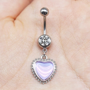 Detail of silver heart navel ring with purple crystal gemstone held in palm