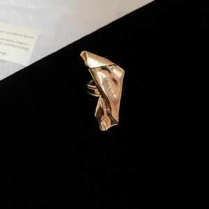 Macro shot of irregular pleated golden necklace with geometric folds on black velvet