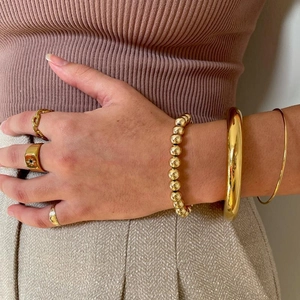 Set of stackable 18k gold plated stainless steel bangles and rings on female wrist