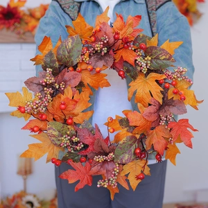 Close-up of a large autumn wreath featuring faux maple leaves and orange berries