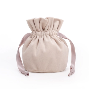 Detail view of a beige velvet drawstring pouch with soft texture and knotted cord ribbons