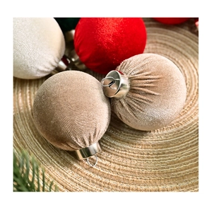 Close-up of velvet Christmas ball ornaments in beige red and green on woven mat