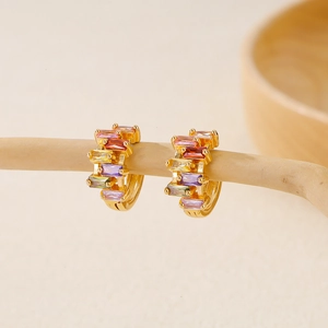 Close-up of golden hoop earrings featuring baguette-cut multicolored zircon stones