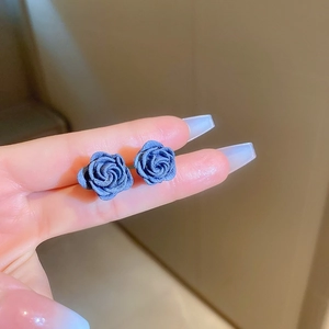 Close-up of vintage navy blue flocked rose stud earrings held to show texture and size
