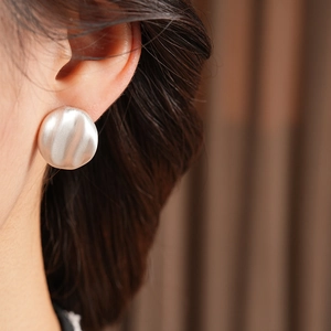 Macro side view of elegant silver irregular wavy geometric earrings worn by model