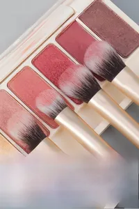 Macro detail of black and gold eye brushes picking up high-pigment shimmer eyeshadow powder