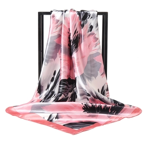 Pink and grey floral silk square scarf elegantly draped on a minimalist black display stand