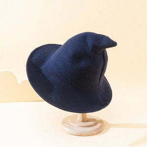 Detail of navy blue knitted witch hat with pointed top on a wooden stand