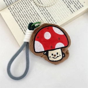 Close-up of a plush mushroom keychain with a red polka dot cap and smiling face
