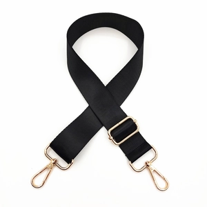 Detail of adjustable black nylon bag strap with polished gold hardware and swivel clips