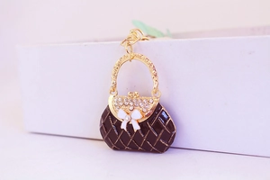 Macro detail of handbag keychain with black enamel, rhinestones and white bow