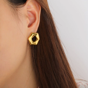 Close-up of minimalist gold-plated hexagonal hoop earring worn on an earlobe for styling