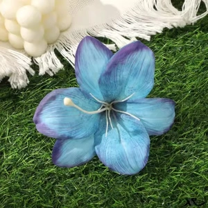Macro view of blue and purple gradient lily hair clip on green grass background