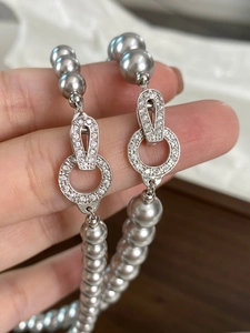 Macro shot of silver-grey pearl necklace with a rhinestone-studded metal clasp