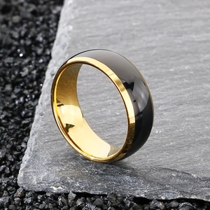 Detailed close-up of two-tone polished black and gold ring on a grey stone slab