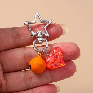 Star-shaped clasp keychain with orange bell and transparent heart filled with red sequins