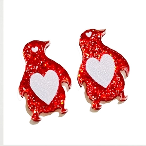 Gros plan de boucles d'oreilles pingouins rouges à paillettes avec cœur blanc festif