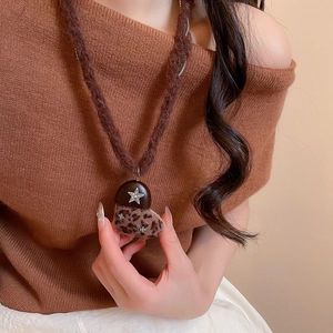 Gros plan du pendentif cœur léopard sur collier en peluche marron porté par un mannequin