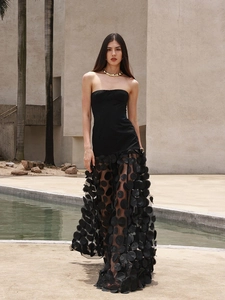 Detail of black strapless evening dress with 3D polka dot tulle skirt in outdoor setting
