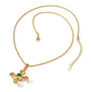Detailed shot of 18k gold cross pendant featuring a green gemstone and rope chain