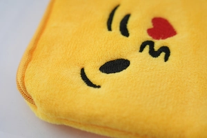 Close-up of cute yellow plush coin purse with detailed kiss face embroidery texture