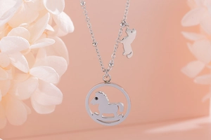 Macro d'un collier pendentif cheval à bascule argenté avec chaîne à billes et fleurs
