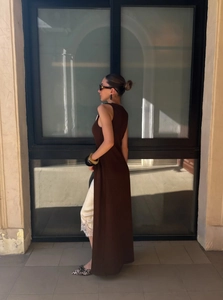 Detail of a brown sleeveless long vest paired with a white lace-trimmed silk dress