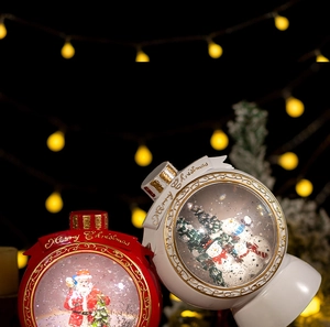 Close-up of Santa and Snowman crystal snow globes with golden Merry Christmas lettering