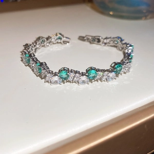 Close-up of elegant silver bracelet with emerald green and white cubic zirconia stones