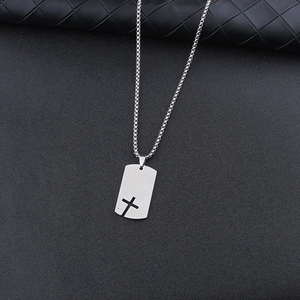 Detail of silver stainless steel dog tag necklace with cutout cross on dark leather