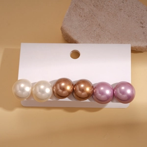 Detailed view of 3 pairs of round faux pearl studs in white, bronze, and purple colors