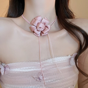 Detail of pink fabric flower choker with long ribbon streamers worn by a model