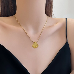 Gold shell pendant necklace on snake chain for women worn by model in minimalist style