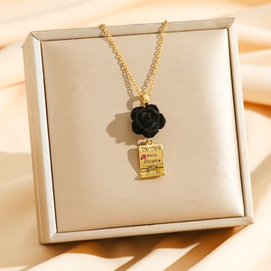 Velvet rose and engraved gold scroll pendant necklace displayed on a jewelry box